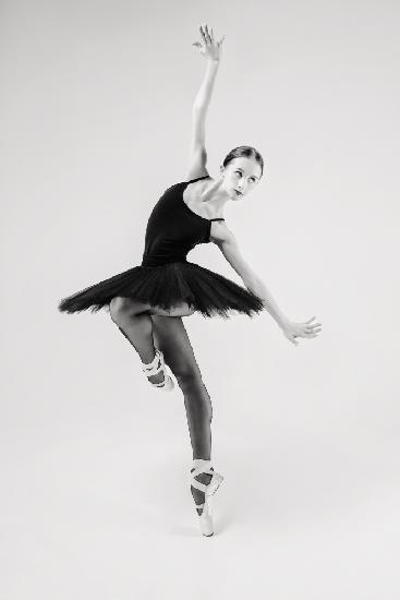 schwarzer Schwan. Ballerina im schwarzen Tutu zeigt Elemente des Balletttanzes in Bewegung