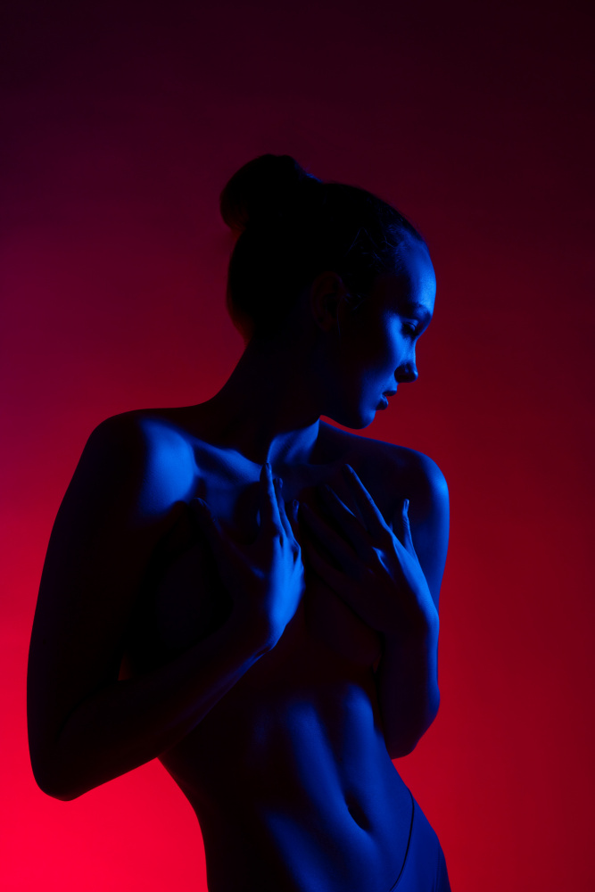 Junge Frau in lässiger Kleidung steht unter Neonlicht von Andrey Guryanov