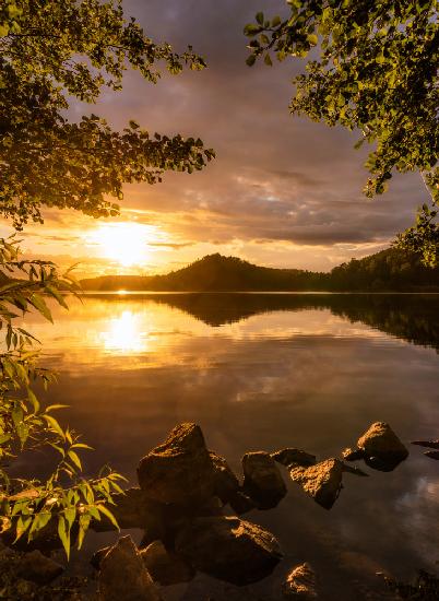 Sonnenuntergang an einem See mit einem kleinen Berg im Hintergrund