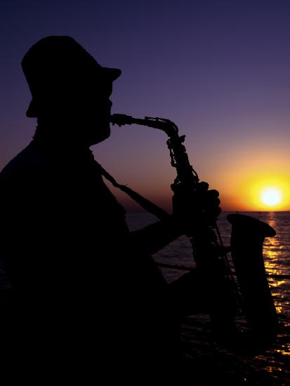 ein Musiker,der bei Sonnenuntergang Saxophon spielt