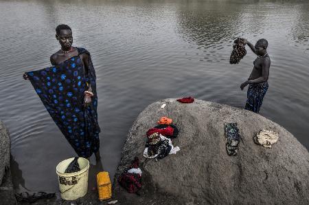 Frauen des Mundari-Stammes putzen Kleidung im Fluss - Südsudan