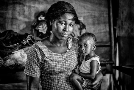 Mutter und ihr Kind in einer Nähfirma in Ghana.