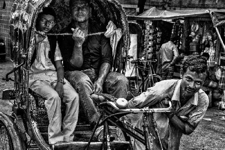Rikschafahrer mit zwei Kunden in den Straßen von Bangladesch