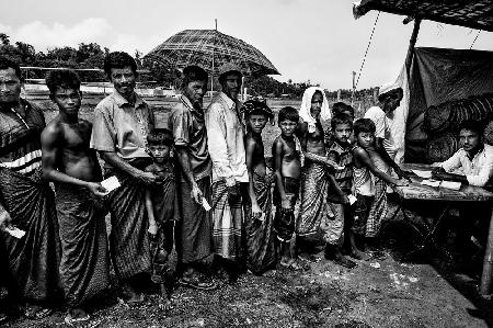 Rohingya-Flüchtlinge stehen Schlange,um einige Gegenstände für den Bau ihrer Häuser zu bekommen.