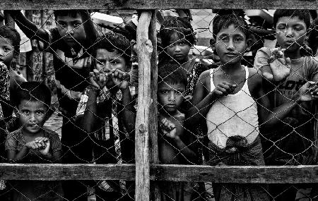 Rohingya-Kinder beobachten die Verteilung von Lebensmitteln in Kisten an andere Kinder.