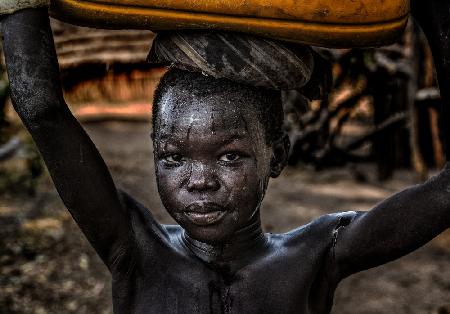 Südsudanesisches Kind,das einen Wasserbehälter trägt
