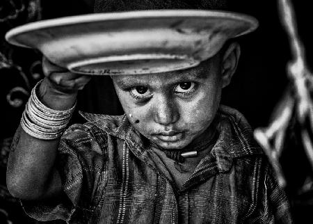 Trauriges Rohingya-Flüchtlingskind zeigt mir seinen leeren Teller mit Essen.
