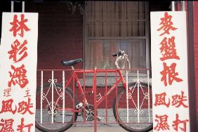 Bicycle at metal bars with Chinese board , Singapore (photo) 