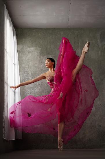 Die Pose einer Ballerina im roten Kleid