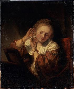 Junge Frau, die Ohrringe anprobiert 1657