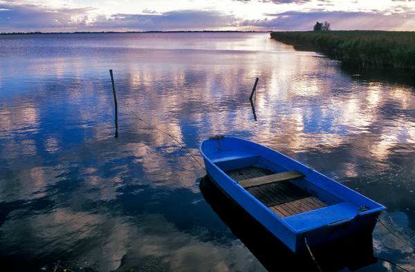 Blaues Boot am Seeufer mit Wolkenstimmung von Robert Kalb